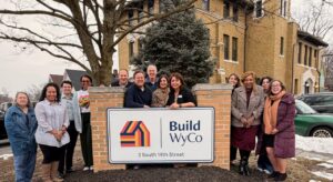 Board members posed around Build WyCo building signage