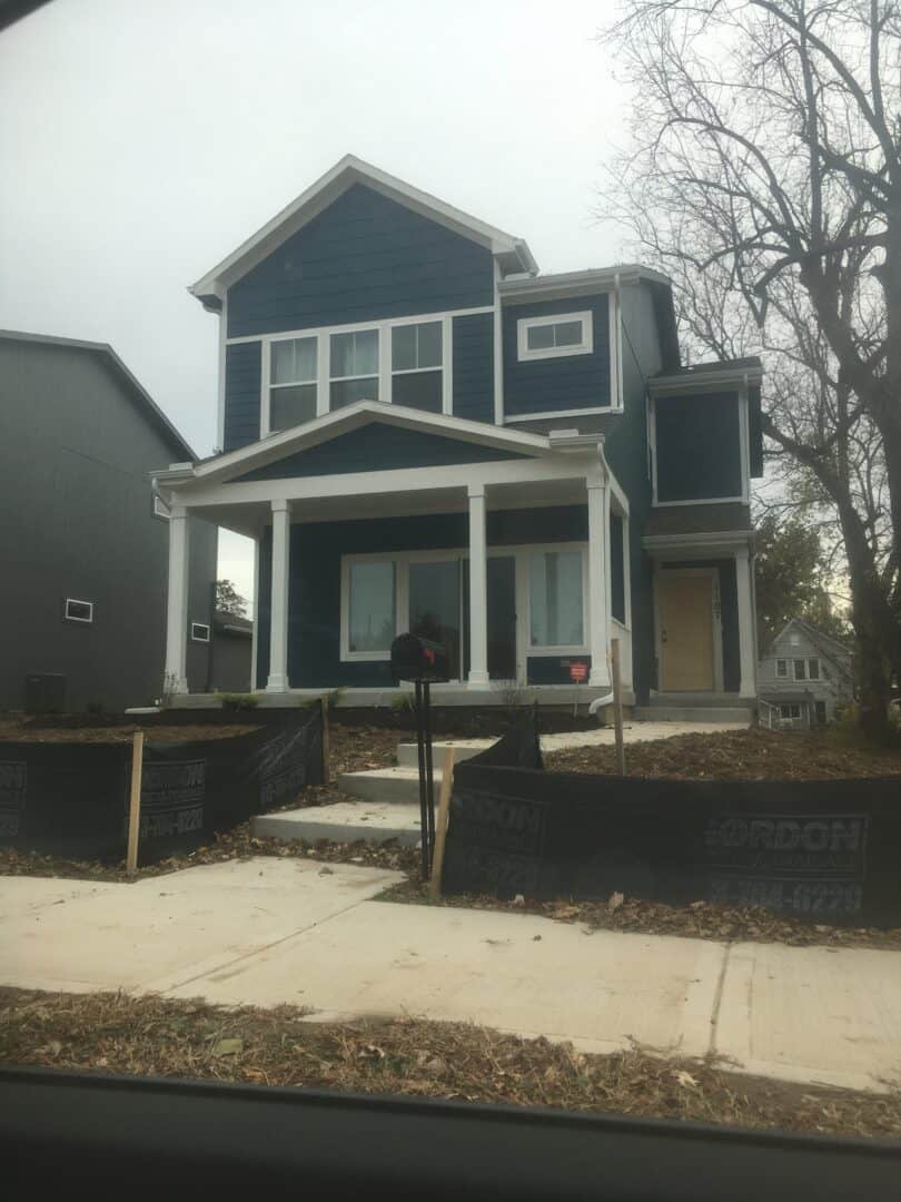 A two-story home with 2 visible windows on the second story and a large sliding door on the ground level. The front entry is to the right facing the house.