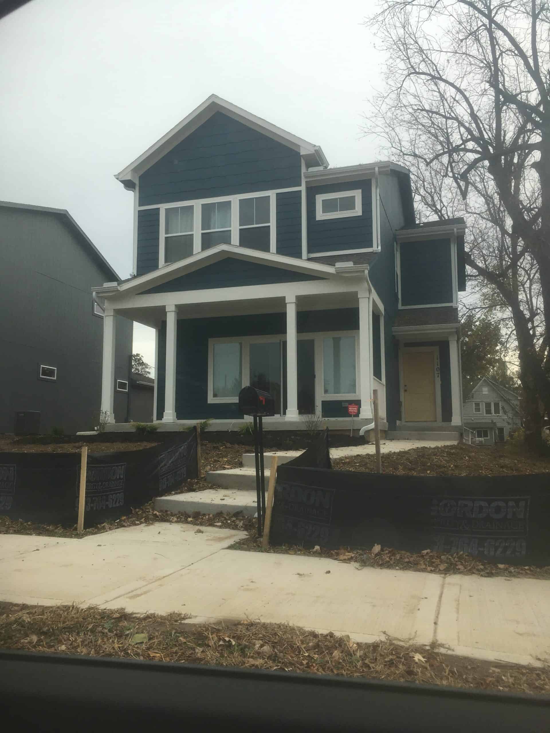 A two-story home with 2 visible windows on the second story and a large sliding door on the ground level. The front entry is to the right facing the house.