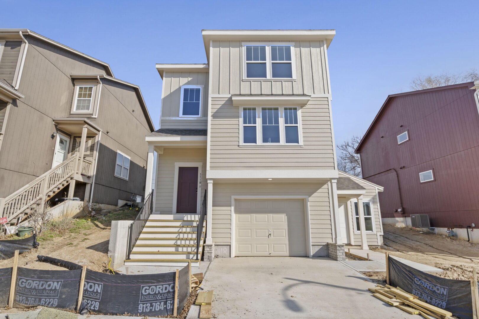 A brand new multi-story home with a tuck under garage, light brown exterior and white trim.