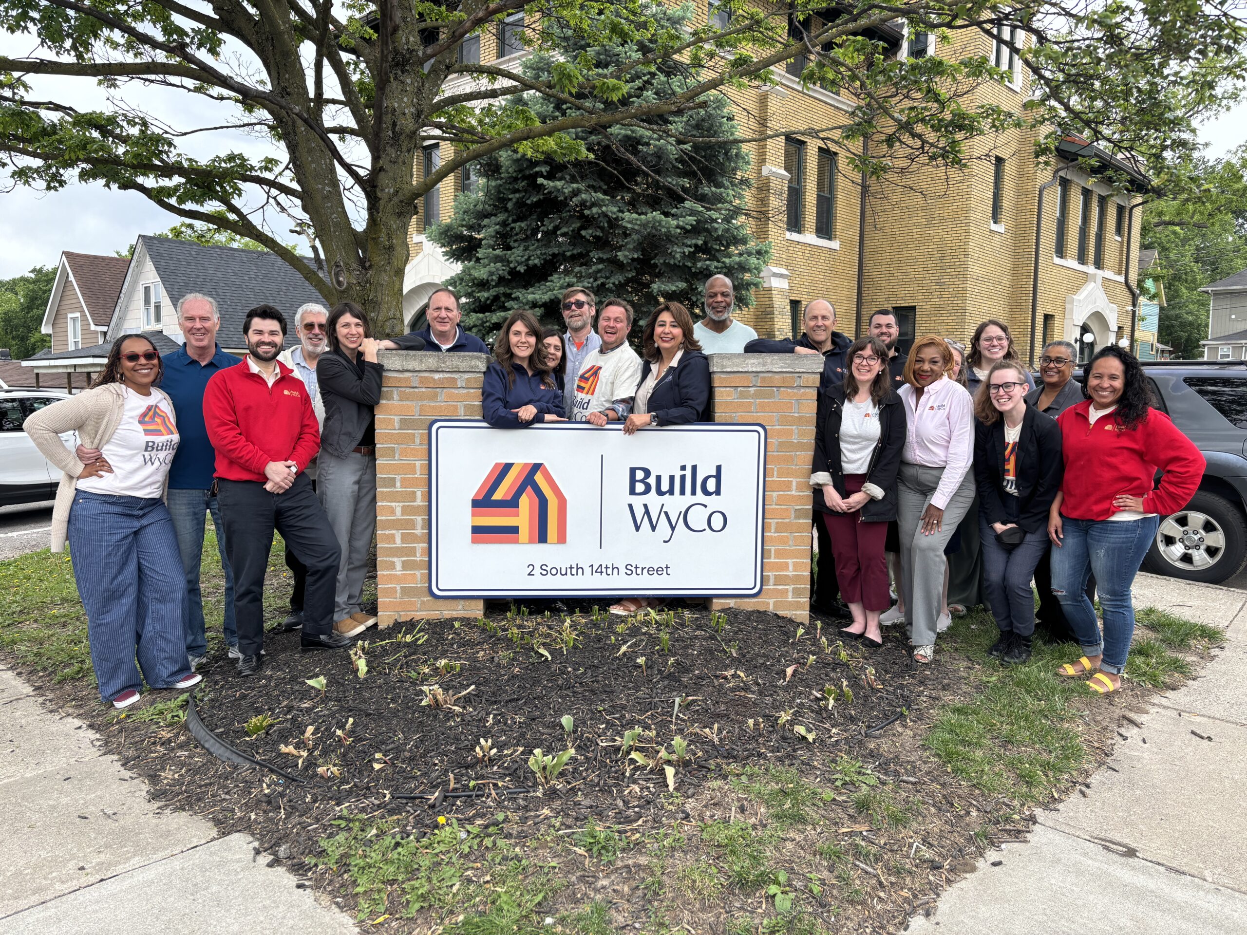 Board members posed around Build WyCo building signage