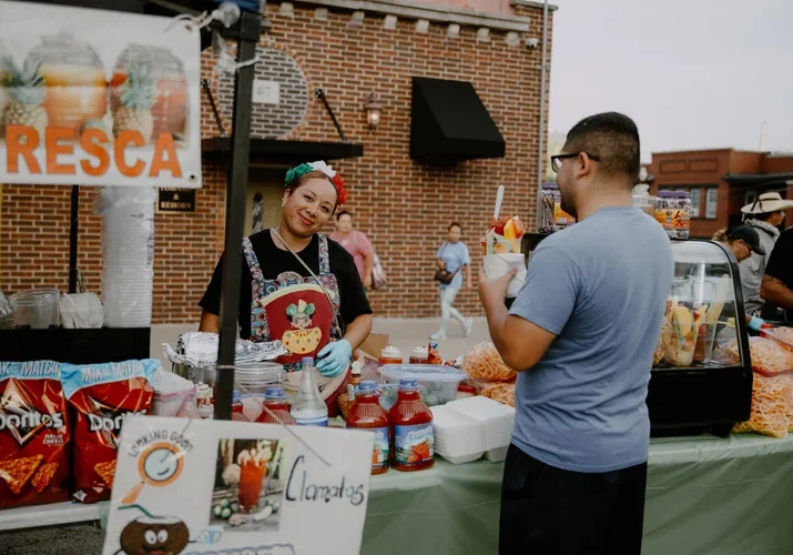 A woman works at an outdoor food stand selling fruit.