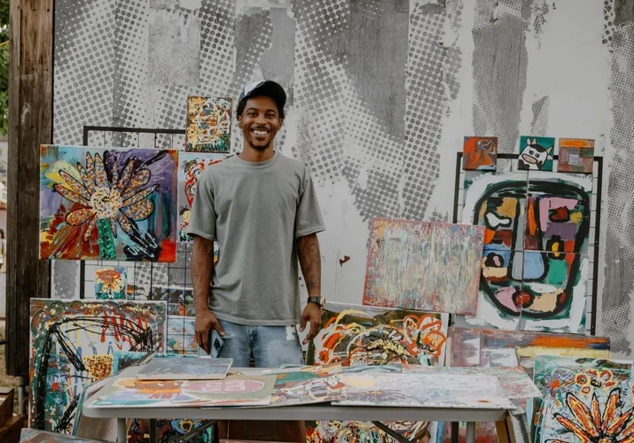 A man stands at a table selling art.