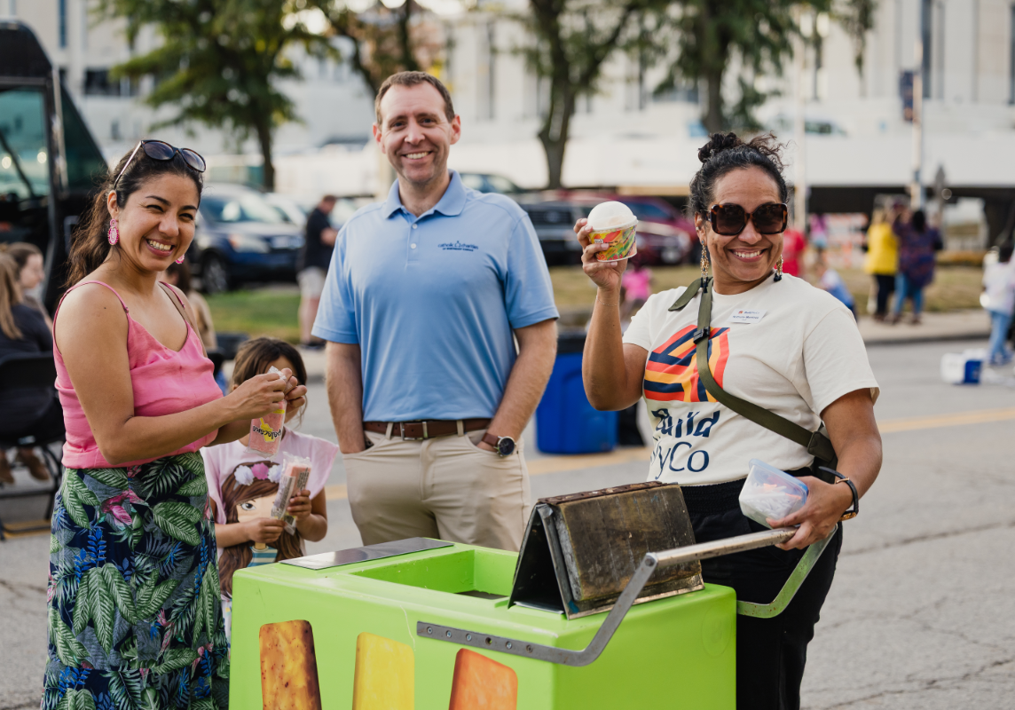 A woman holding some ice cream with a family standing nearby.